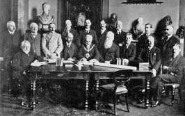 A photograph by Hamilton Toovey of the signing of the contract by the Constable of St Helier and his Electric Lighting Committee on 28 April 1924. Those in the picture are John Edwin Pinel, Constable of St Helier, P A Aubin, G T Day, E P Falle, F G Gallichan, Walter Le Feuvre, G J Le Masurier, H Le Masurier, Francis Le Sueur, Edmund Nicolle, J W Orviss, A H Preece, John Renouf, J R Sinnatt, Edward Voisin, and F A E Voisin
