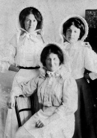 A mother and two daughters wearing matching bonnets, probably for the garden rather than for farm work