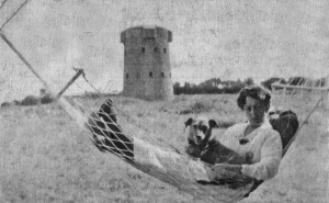 Clarissa May Cutler, née Le Geyt, her hammock positioned in front of a coastal tower, not positively identified but believed to be in Grouville Bay