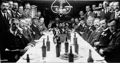 In July 1916, a committee of local merchants organised a ‘Gift to the Royal Navy’ scheme to donate over 250 tonnes of potatoes from Jersey to the Royal Navy, created from farmers contributing a portion of their crop. This image shows representatives of the merchants supporting the donation scheme gathered in the cabin of the SS Notts at the time of shipment.