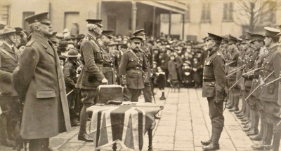 In a Royal Square ceremony held early in 1916, the Lieutenant Governor General Sir Alexander Rochfort awards Long Service and Good Conduct Medals to Quarter Master Sergeant Hill of the Militia’s 3rd (Town) Battalion.
