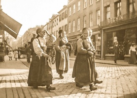 Breton workers cross the cobbled street in the late 19th century