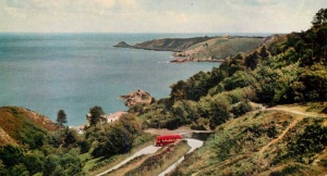 A red bus descends the hill