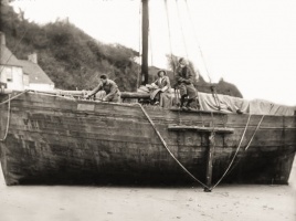 Working on a large fishing vessel, possibly part of the oyster fleet, in the harbour