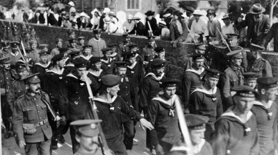 The funeral of German prisoner of war Karl Brundig who died aged 21 on 21 August 1915 following an epileptic fit while being held in the recently opened Blanches Banques POW camp. He burial took place in St Peter’s Churchyard accompanied by a cortege of 50 comrades who were permitted to accompany the coffin from St Peter’s Barracks where it had been resting. The image shows them passing a large crowd of curious local onlookers who gathered for the occasion.
