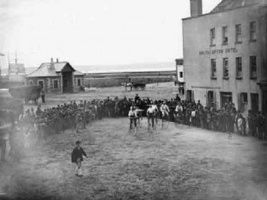 A crowd gathers round men with penny farthing bicycles outside the Southampton Hotel